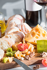 Image showing Wine, baguette and cheese on wooden background