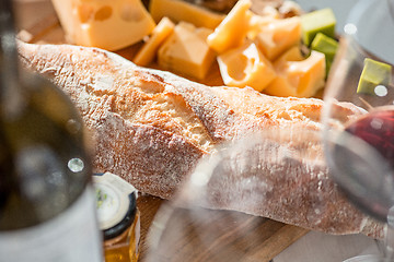 Image showing Wine, baguette and cheese on wooden background