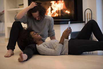 Image showing multiethnic couple using tablet computer on the floor