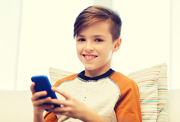 Image showing boy with smartphone texting or playing at home