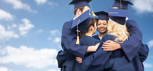Image showing happy students or bachelors hugging over blue sky