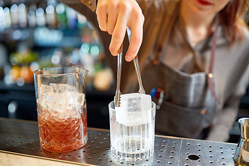 Image showing bartender adding ice cube into glass at bar