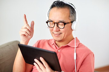 Image showing man with tablet pc and headphones at home