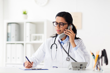 Image showing doctor with clipboard calling on phone at hospital