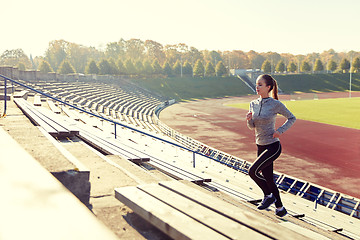 Image showing happy young woman running upstairs on stadium