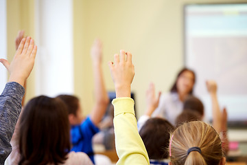 Image showing group of school kids raising hands in classroom