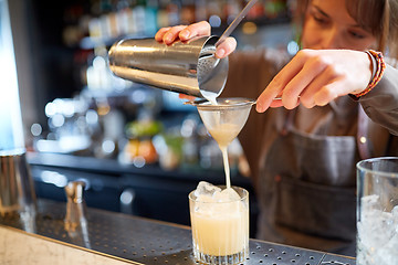 Image showing bartender with cocktail shaker and glass at bar