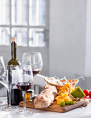 Image showing Wine, baguette and cheese on wooden background