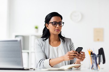 Image showing businesswoman with smartphone and laptop at office