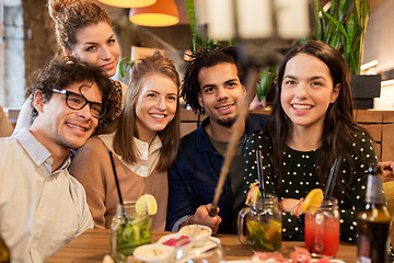 Image showing friends taking selfie by smartphone at bar or cafe