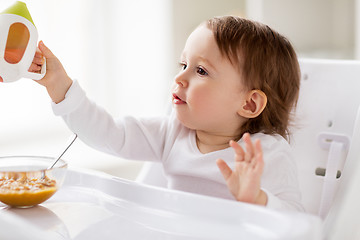 Image showing baby drinking from spout cup in highchair at home