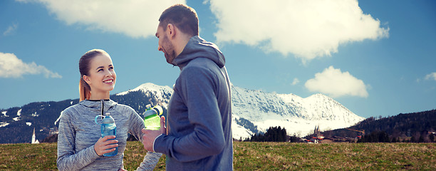 Image showing smiling couple with bottles of water outdoors