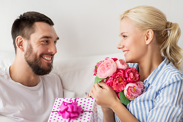 Image showing happy couple with gift box in bed at home