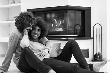 Image showing multiethnic couple used tablet computer on the floor