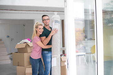 Image showing couple carrying a carpet moving in to new home