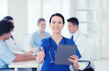 Image showing happy doctor with tablet pc over team at clinic