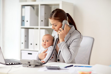 Image showing businesswoman with baby calling on phone at office