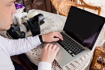 Image showing Man working on laptop at the wooden table outdoors