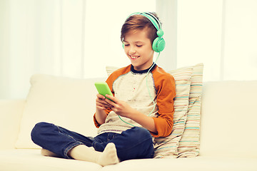 Image showing happy boy with smartphone and headphones at home