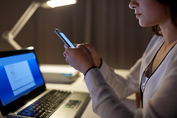 Image showing businesswoman with smartphone at night office
