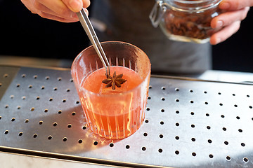 Image showing bartender with glass of cocktail and anise at bar