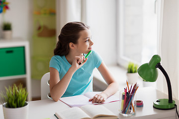 Image showing happy girl with book writing to notebook at home