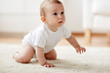 Image showing little baby in diaper crawling on floor at home