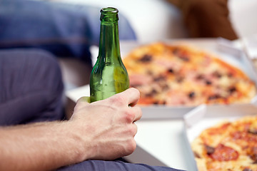 Image showing man with beer bottle and pizza at home