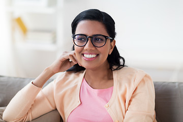 Image showing happy smiling young woman sitting on sofa at home