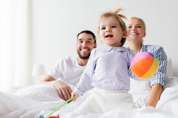 Image showing happy child with toys and parents in bed at home