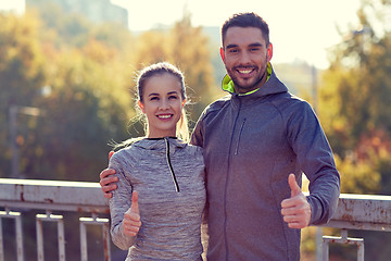 Image showing smiling couple showing thumbs up outdoors