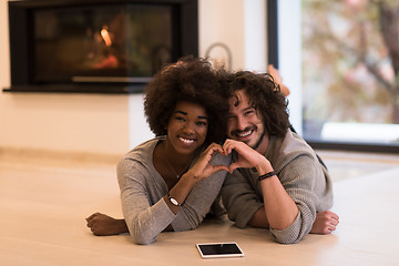 Image showing multiethnic couple showing a heart with their hands on the floor