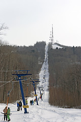 Image showing Snowboarder using a surface lift on the slope.