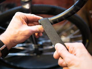 Image showing Guy winds tape on bike