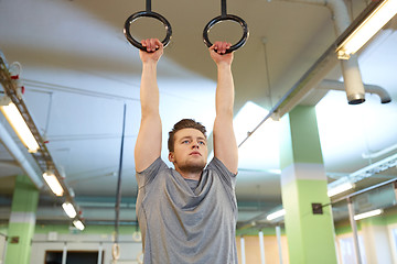 Image showing man exercising and doing ring pull-ups in gym