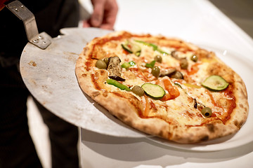 Image showing chef placing pizza from peel to plate at pizzeria