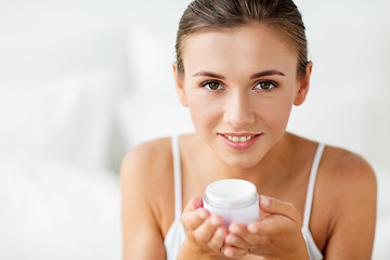 Image showing close up of happy woman holding cream jar