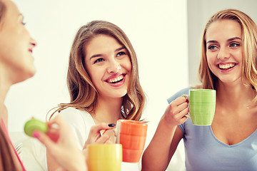 Image showing happy young women drinking tea with sweets at home