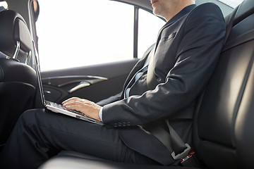 Image showing senior businessman with laptop driving in car