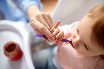 Image showing close up of mother feeding baby with puree at home