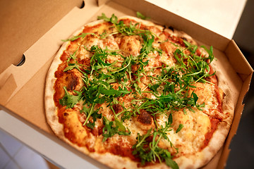 Image showing close up of pizza in box on table at pizzeria