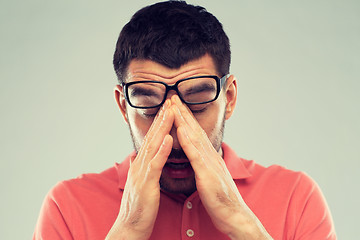 Image showing tired man in eyeglasses rubbing eyes