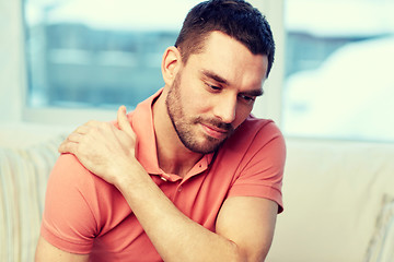 Image showing unhappy man suffering from neck pain at home