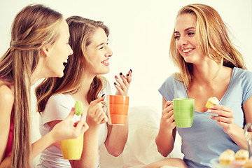 Image showing happy young women drinking tea with sweets at home
