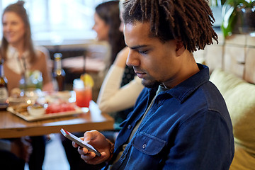 Image showing man with smartphone and friends at restaurant