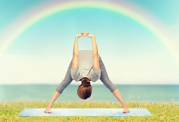 Image showing woman making yoga wide-legged forward bend on mat