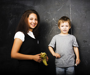 Image showing little cute boy with young teacher in classroom studying at blac