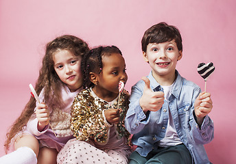 Image showing lifestyle people concept: diverse nation children playing together, caucasian boy with african little girl holding candy happy smiling 