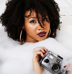 Image showing young afro-american teen girl laying in bath with foam, wearing 