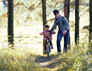 Image showing father learning his son to ride on bicycle outside, real happy f